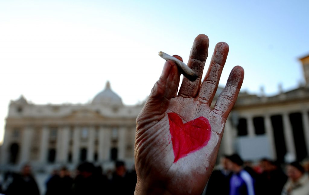 A hand with a heart painted holds a ciga